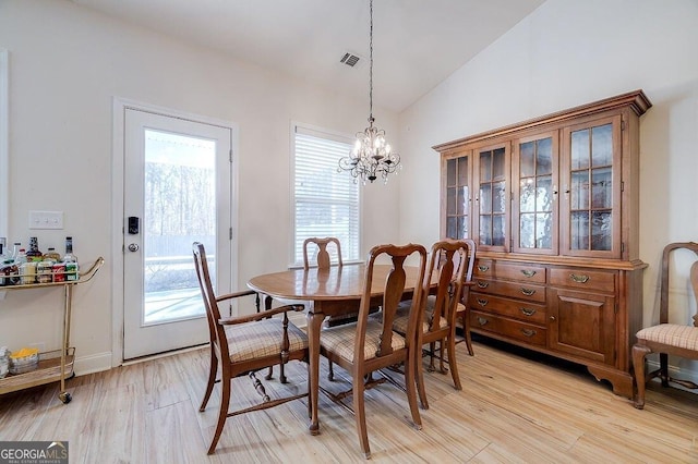 dining space featuring vaulted ceiling, light hardwood / wood-style floors, and an inviting chandelier