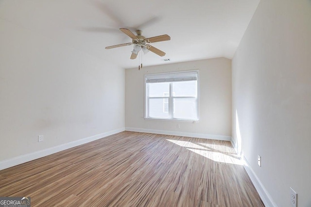 spare room featuring light wood-type flooring, vaulted ceiling, and ceiling fan