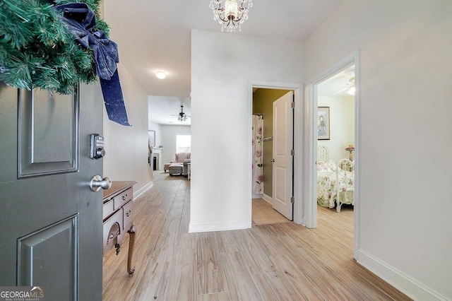 entrance foyer featuring ceiling fan with notable chandelier and light wood-type flooring