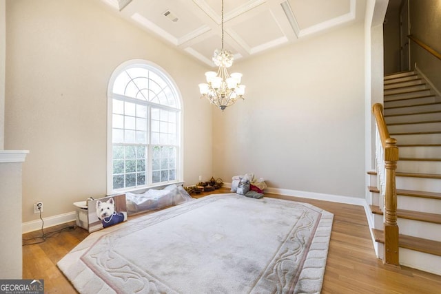 bedroom with a chandelier, beam ceiling, light hardwood / wood-style flooring, and coffered ceiling