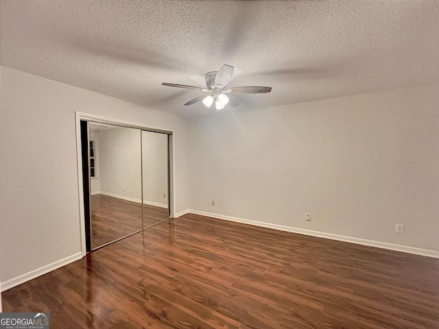 unfurnished bedroom with a textured ceiling, a closet, ceiling fan, and dark wood-type flooring