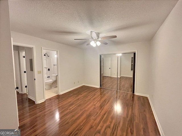 unfurnished bedroom with connected bathroom, ceiling fan, a closet, and dark wood-type flooring