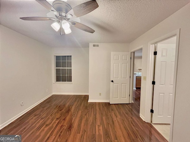 empty room with ceiling fan, dark hardwood / wood-style floors, and a textured ceiling