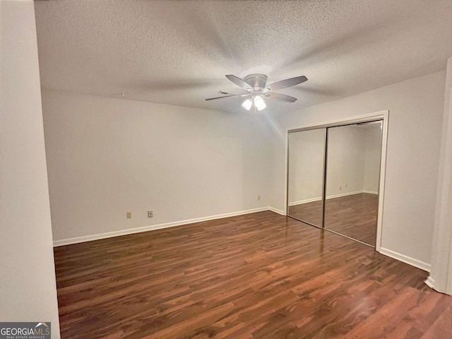 unfurnished bedroom featuring a textured ceiling, dark wood-type flooring, a closet, and ceiling fan