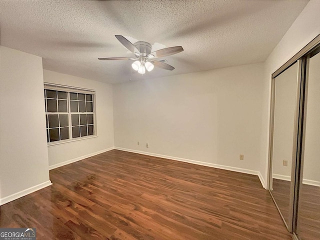 unfurnished bedroom featuring ceiling fan, a textured ceiling, dark hardwood / wood-style flooring, and a closet