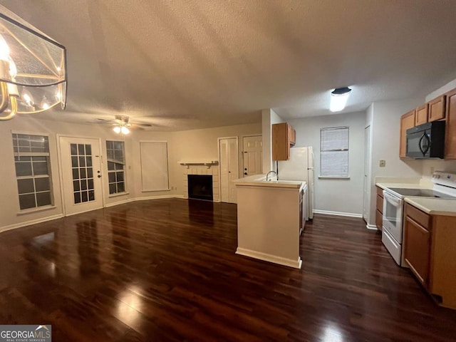 kitchen featuring a textured ceiling, ceiling fan, dark hardwood / wood-style floors, white appliances, and a fireplace