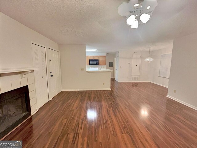 kitchen featuring white appliances, sink, dark hardwood / wood-style floors, a textured ceiling, and kitchen peninsula