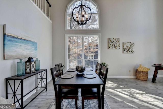 dining space featuring a notable chandelier, a towering ceiling, and hardwood / wood-style flooring