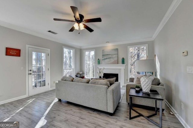 living room featuring ceiling fan, crown molding, a wealth of natural light, and hardwood / wood-style floors