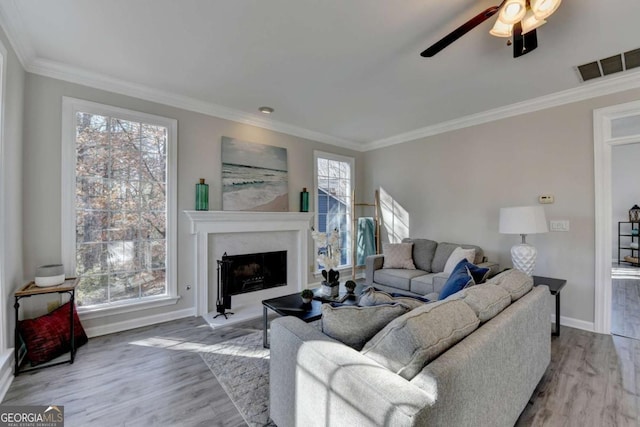 living room featuring light hardwood / wood-style floors, ceiling fan, and ornamental molding