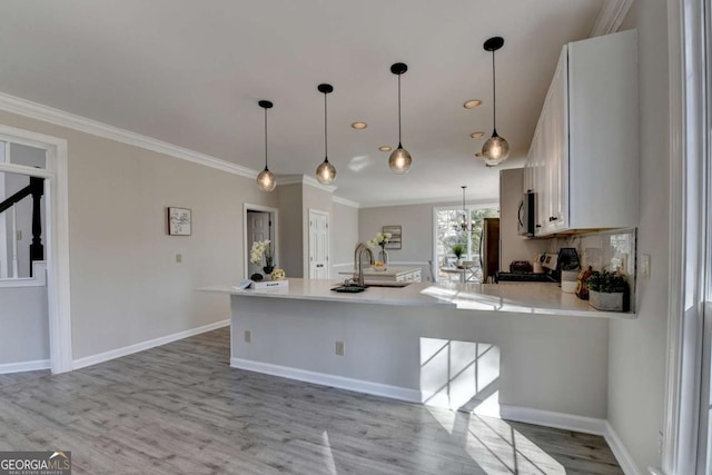 kitchen featuring decorative light fixtures, light wood-type flooring, stove, and white cabinetry