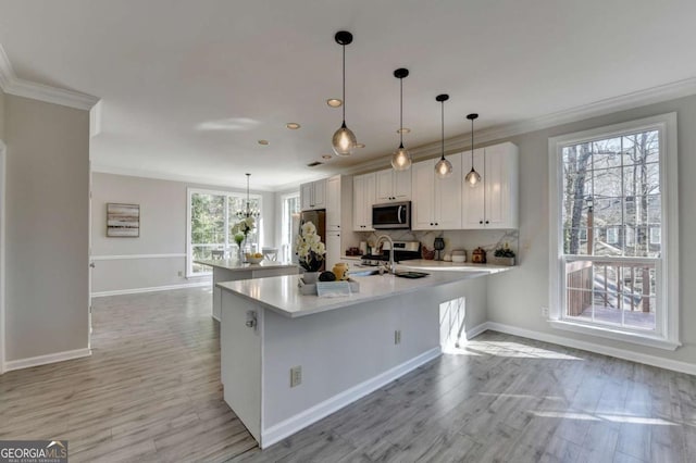 kitchen featuring pendant lighting, stainless steel appliances, crown molding, white cabinets, and sink