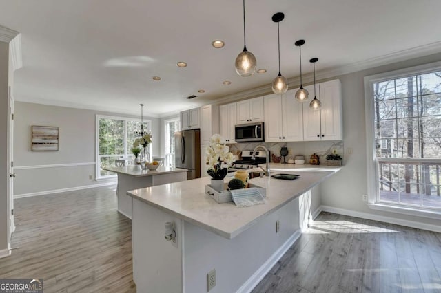 kitchen featuring appliances with stainless steel finishes, white cabinets, backsplash, and decorative light fixtures