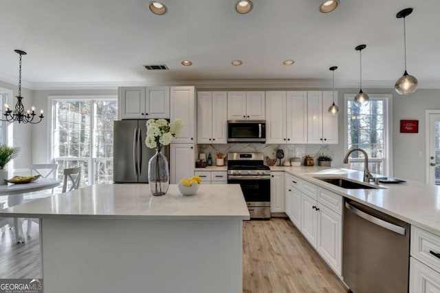 kitchen featuring appliances with stainless steel finishes, crown molding, pendant lighting, and white cabinetry