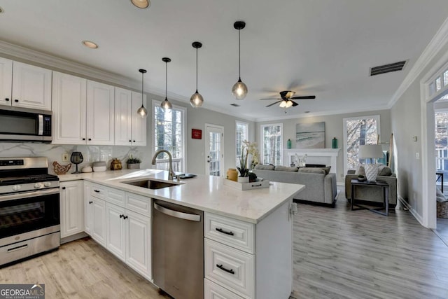 kitchen featuring appliances with stainless steel finishes, kitchen peninsula, decorative backsplash, sink, and white cabinetry