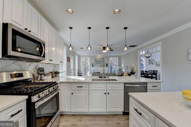 kitchen with pendant lighting, stainless steel appliances, white cabinets, ceiling fan, and sink