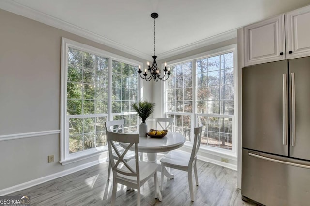 dining space with a notable chandelier, light wood-type flooring, and crown molding