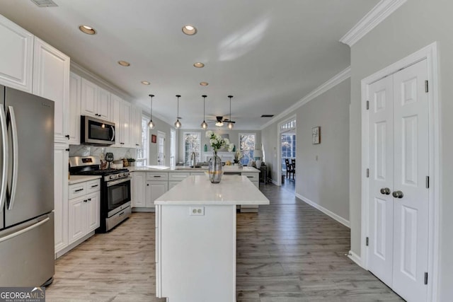 kitchen featuring white cabinets, stainless steel appliances, decorative light fixtures, and kitchen peninsula