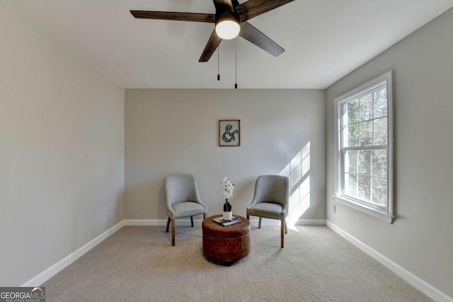 sitting room with ceiling fan and light colored carpet