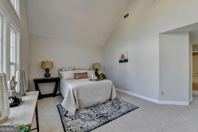 carpeted bedroom with high vaulted ceiling