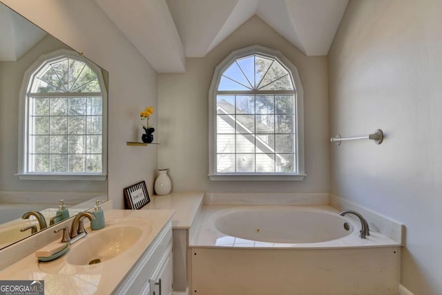 bathroom featuring vanity, a washtub, a wealth of natural light, and vaulted ceiling