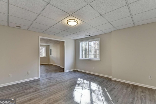 empty room with a paneled ceiling and dark hardwood / wood-style flooring