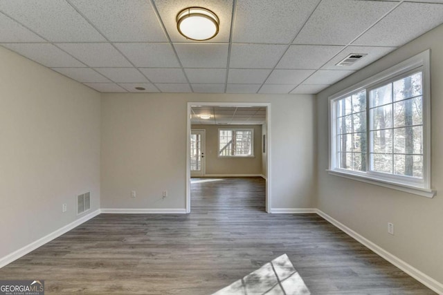 empty room with dark hardwood / wood-style flooring and a paneled ceiling