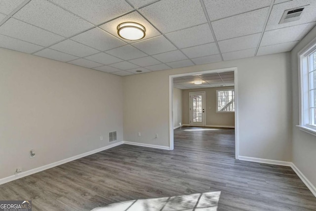 spare room with a paneled ceiling and dark hardwood / wood-style floors