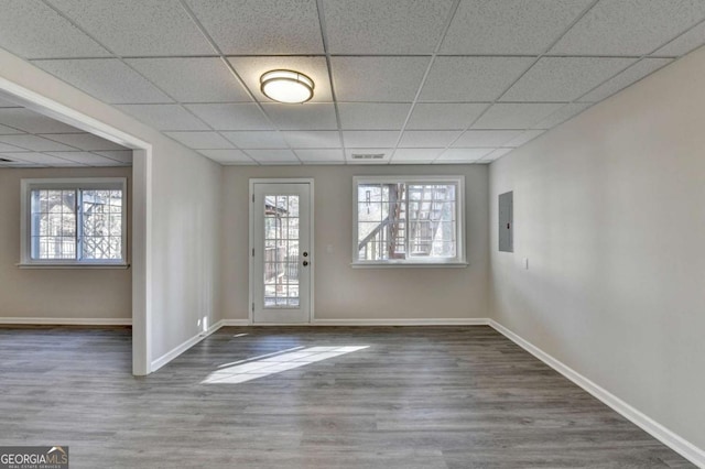 interior space with dark hardwood / wood-style flooring, a drop ceiling, and electric panel