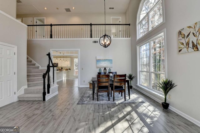 dining space featuring a notable chandelier, a towering ceiling, and hardwood / wood-style flooring