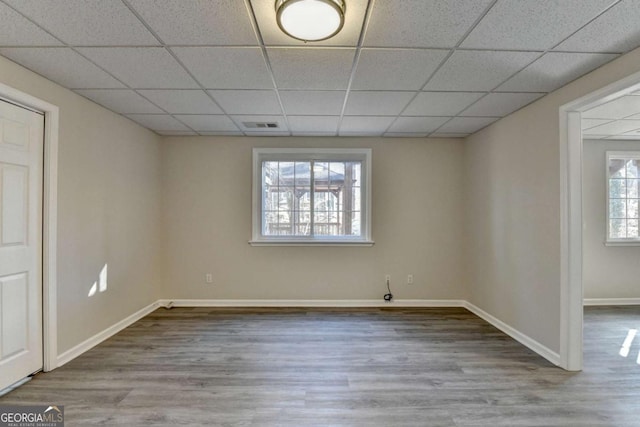 spare room with light hardwood / wood-style floors, plenty of natural light, and a drop ceiling