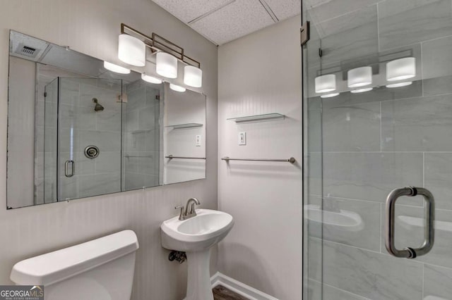 bathroom with toilet, a drop ceiling, walk in shower, and sink