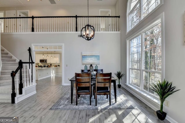 dining area featuring a high ceiling, a chandelier, and hardwood / wood-style floors