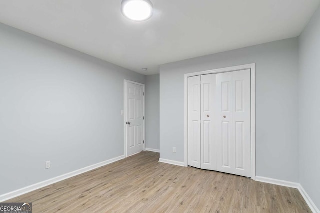 unfurnished bedroom featuring light wood-type flooring and a closet