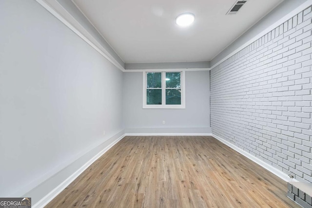 unfurnished room featuring light wood-type flooring and brick wall