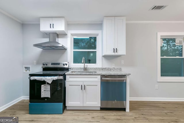 kitchen featuring white cabinets, appliances with stainless steel finishes, wall chimney exhaust hood, and sink