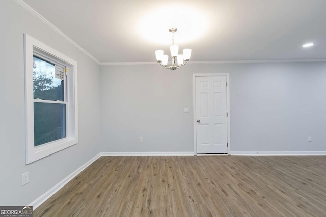 empty room featuring hardwood / wood-style flooring, crown molding, and a notable chandelier