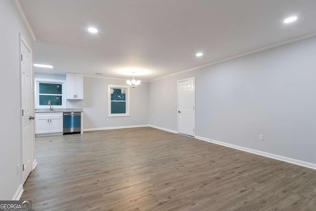 unfurnished living room featuring hardwood / wood-style floors, ornamental molding, and an inviting chandelier