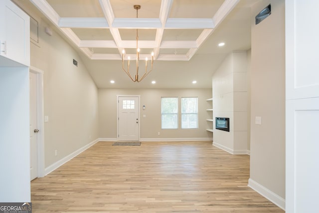 entrance foyer featuring coffered ceiling, light hardwood / wood-style flooring, beamed ceiling, a large fireplace, and a chandelier