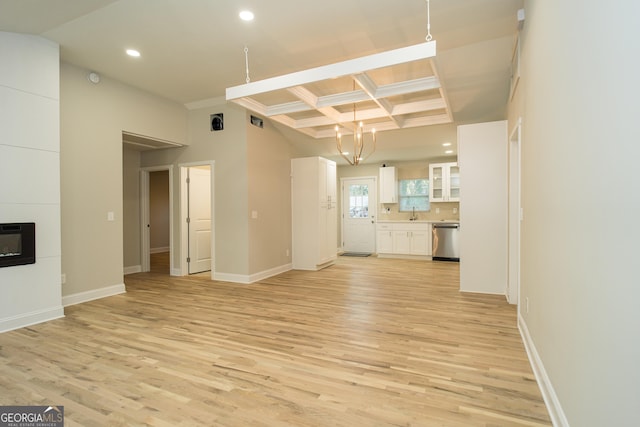 unfurnished living room with beam ceiling, a large fireplace, coffered ceiling, and light wood-type flooring