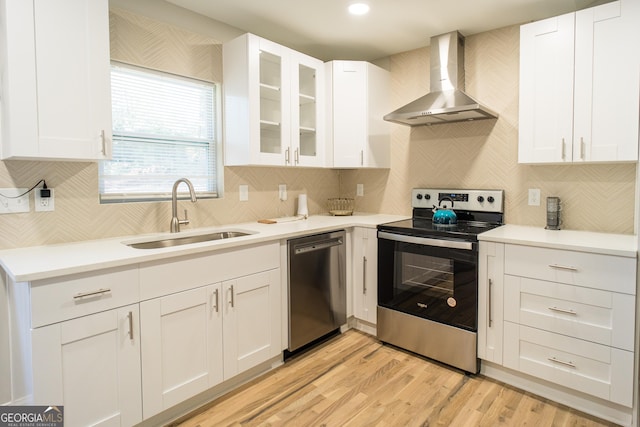 kitchen with white cabinets, appliances with stainless steel finishes, wall chimney exhaust hood, and sink