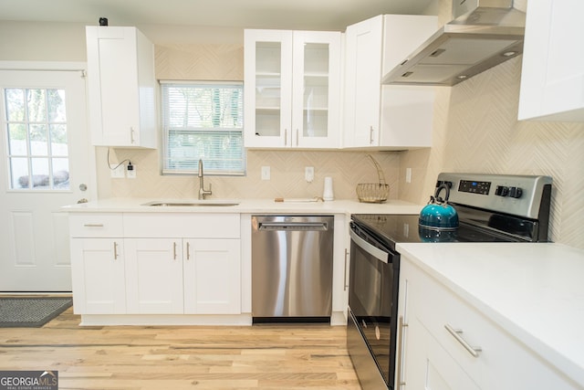 kitchen featuring white cabinets, sink, wall chimney exhaust hood, decorative backsplash, and stainless steel appliances