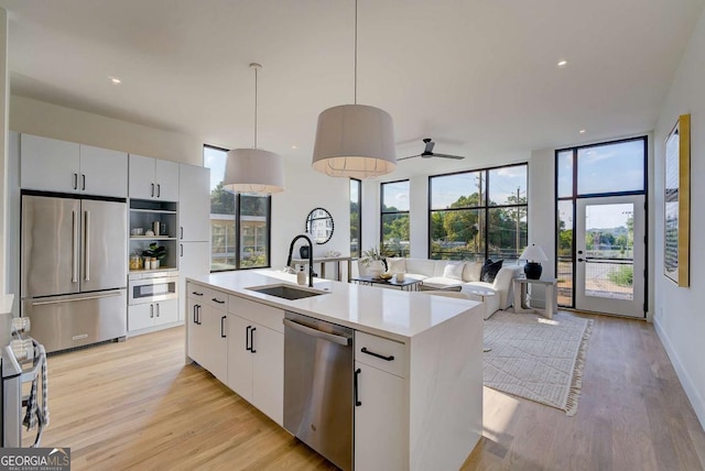 kitchen with pendant lighting, sink, an island with sink, white cabinetry, and stainless steel appliances