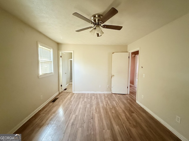 unfurnished bedroom featuring ceiling fan, wood-type flooring, and a textured ceiling