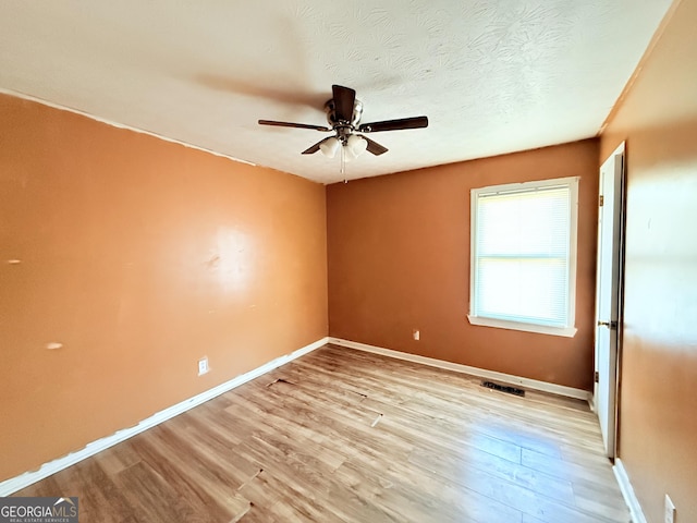 empty room featuring ceiling fan, a textured ceiling, and light hardwood / wood-style flooring