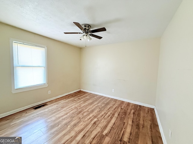 empty room with ceiling fan and light hardwood / wood-style flooring