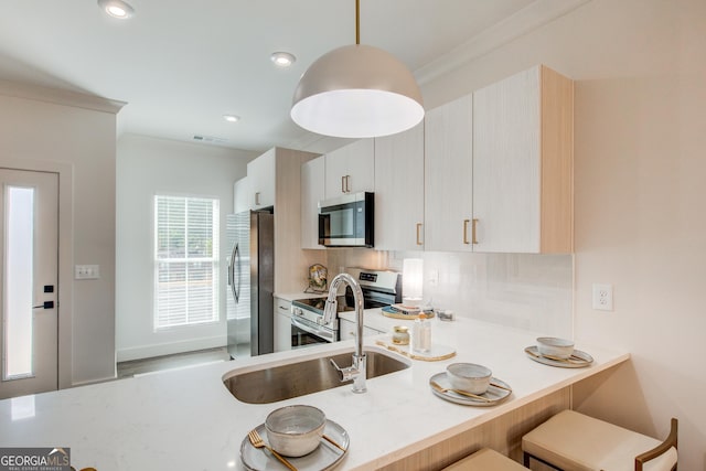 kitchen with stainless steel appliances, ornamental molding, pendant lighting, decorative backsplash, and sink