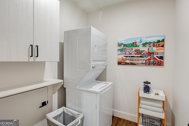 washroom featuring cabinets, stacked washer and clothes dryer, and hardwood / wood-style floors