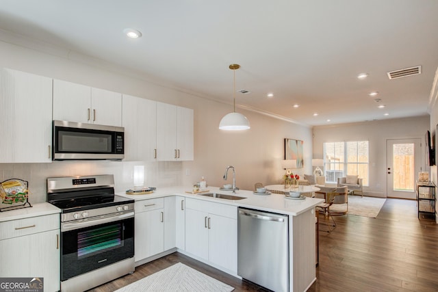 kitchen featuring stainless steel appliances, kitchen peninsula, sink, decorative light fixtures, and backsplash