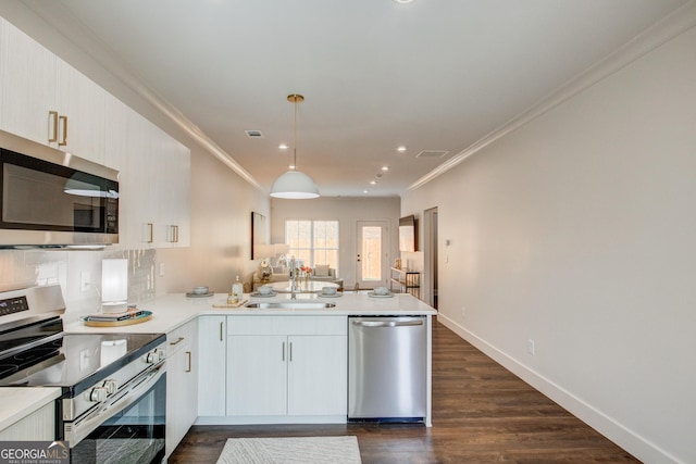 kitchen with kitchen peninsula, hanging light fixtures, dark hardwood / wood-style flooring, appliances with stainless steel finishes, and sink